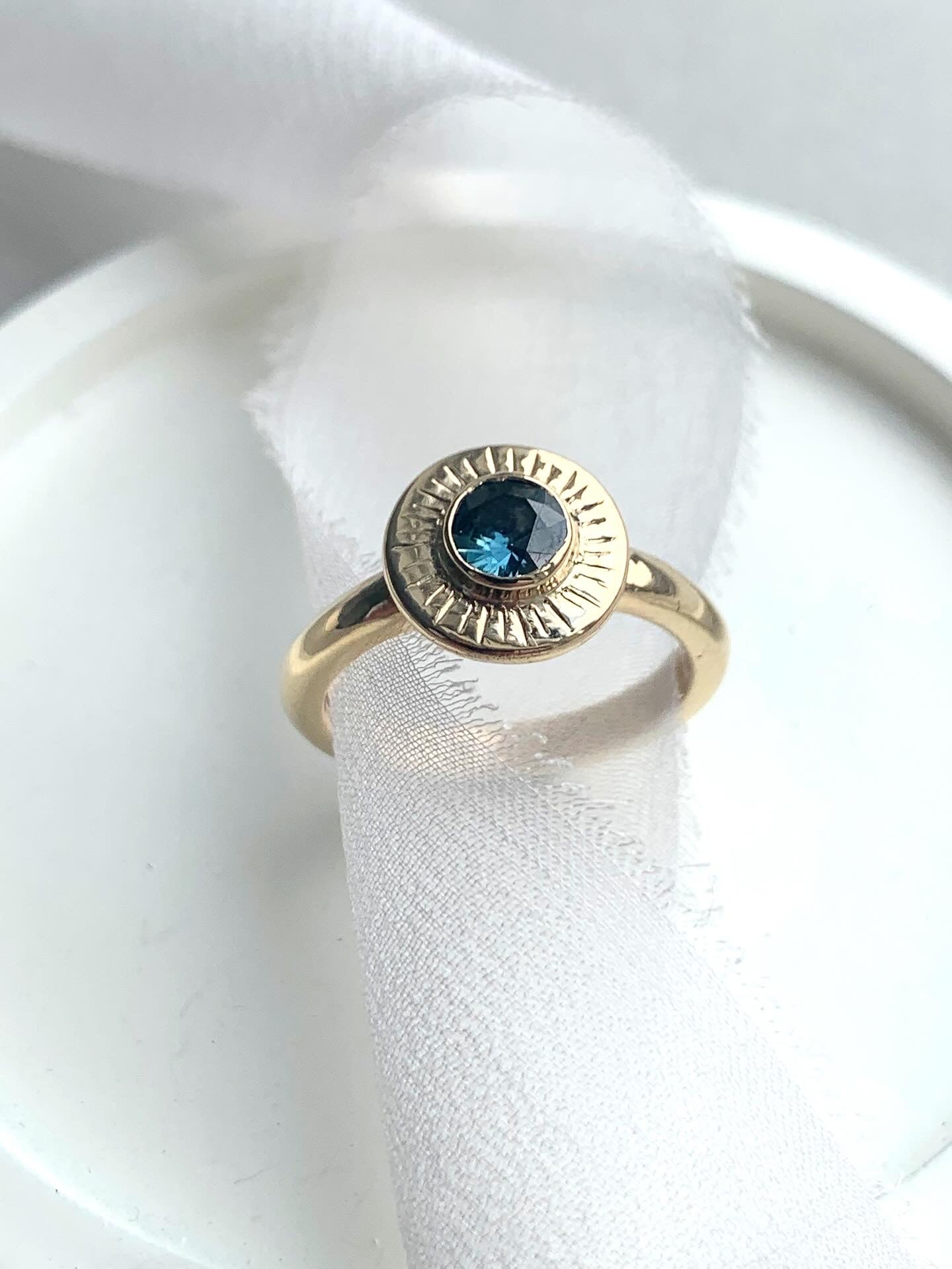 Gold ring with a blue gemstone on a white fabric background
