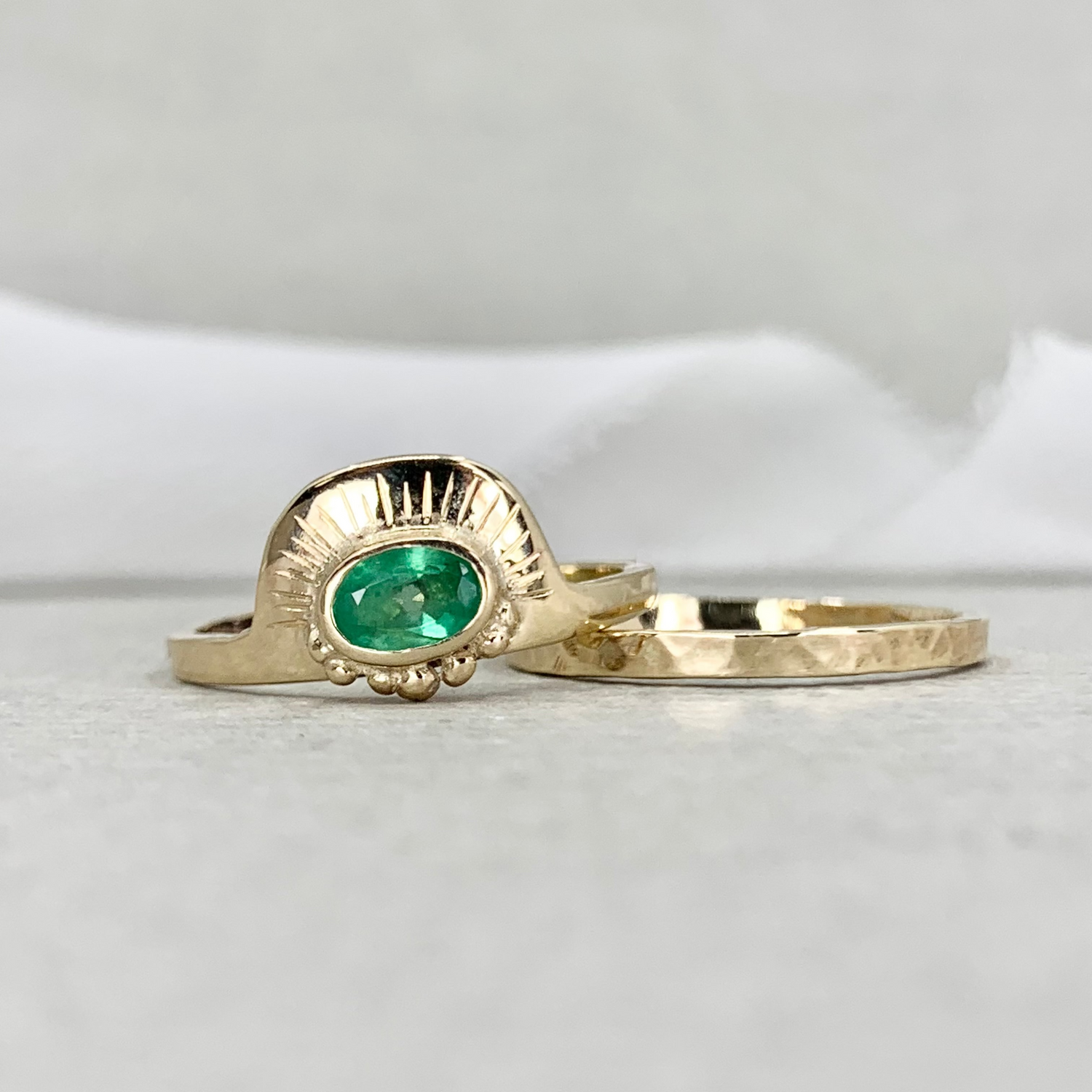 Gold ring with a green gemstone on a light gray background