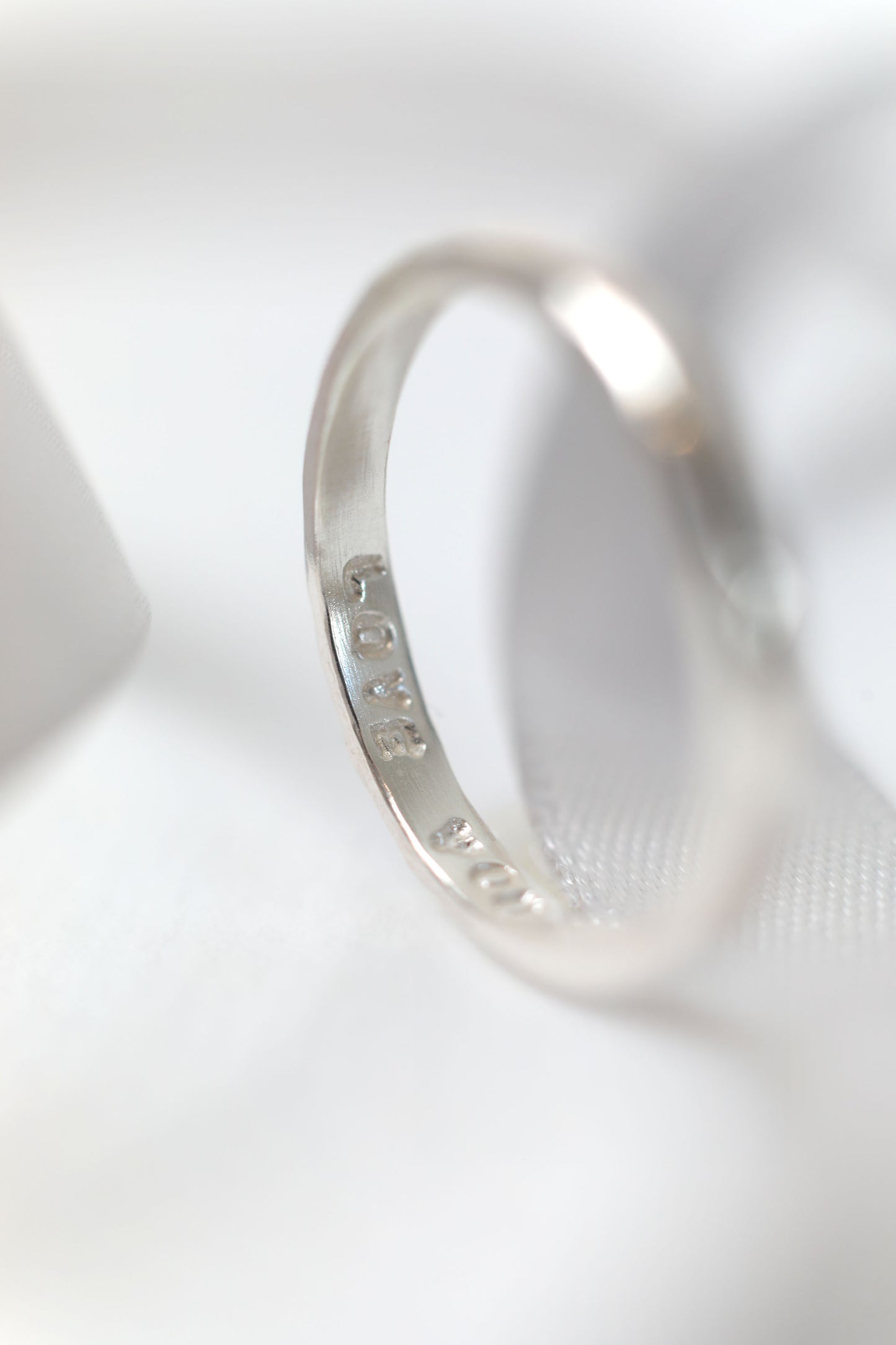 Silver ring with engraved text on a white background