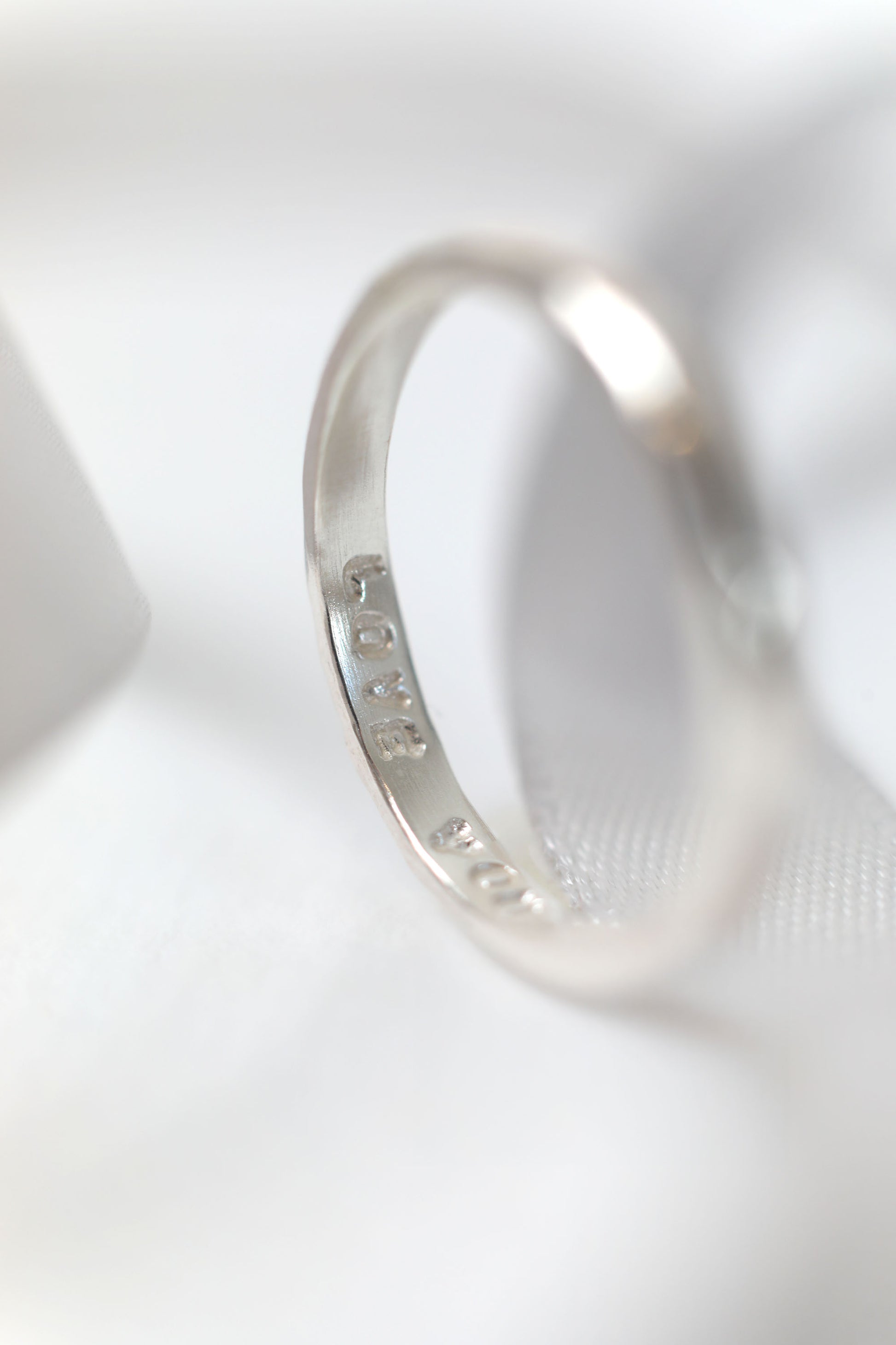 Silver ring with engraved text on a white background