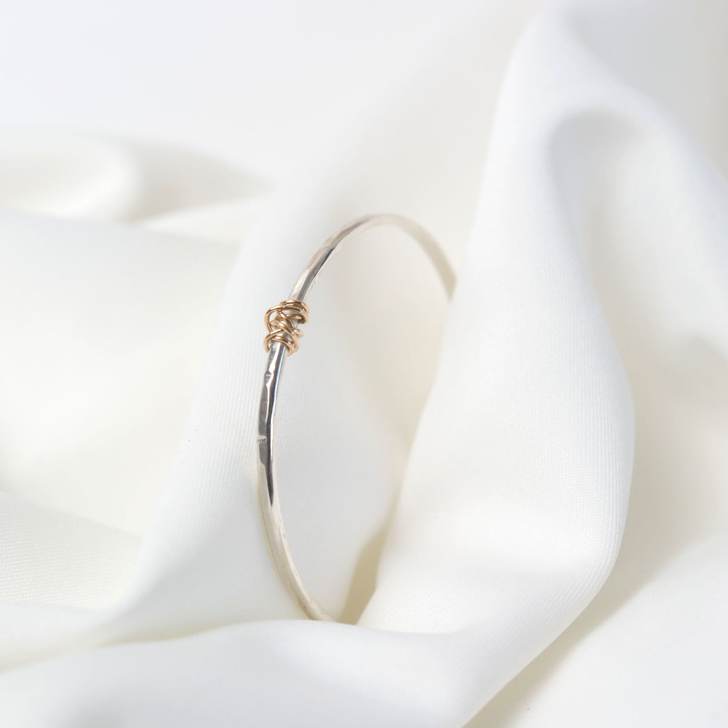 Gold hoop earring on a white fabric background