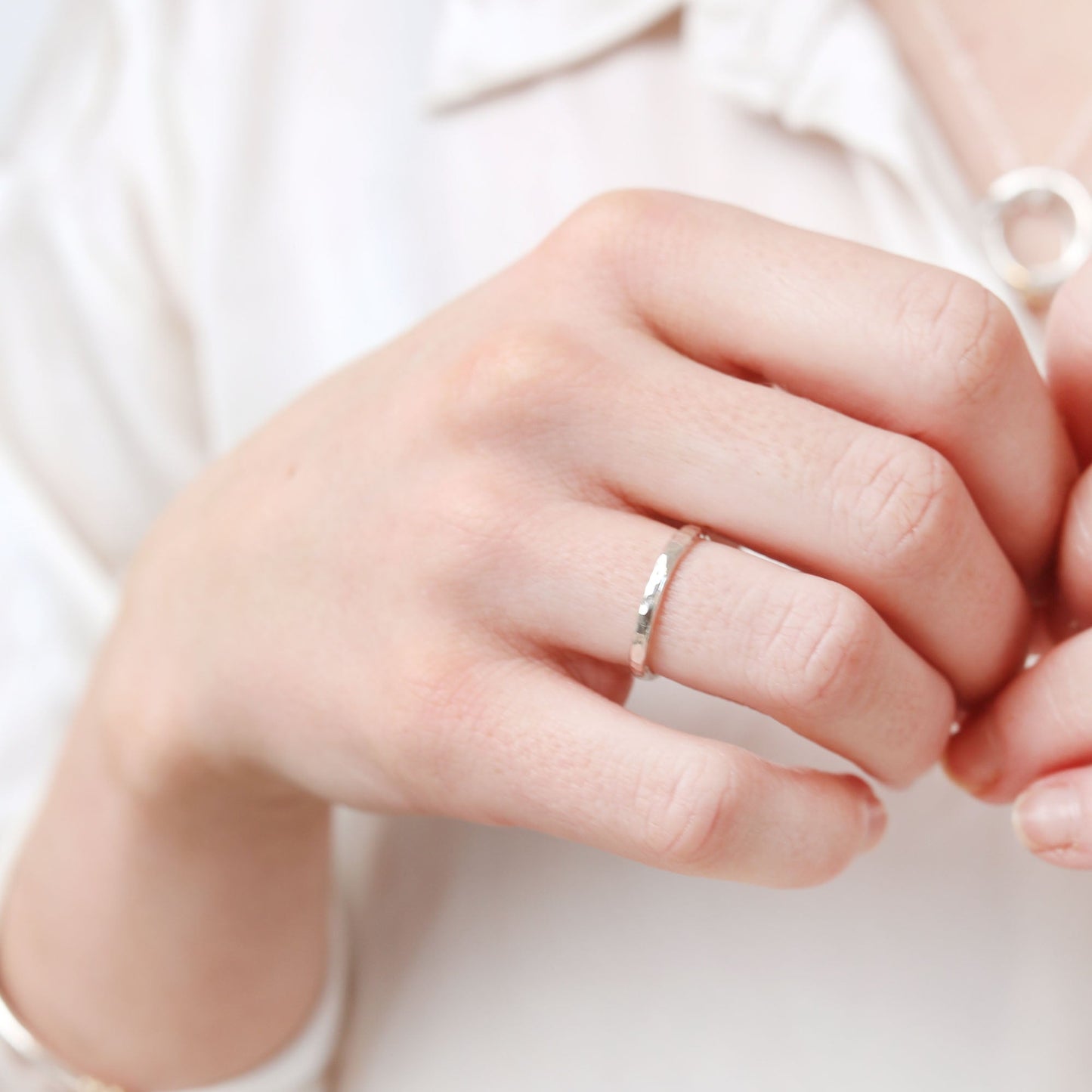 Close-up of a hand wearing a silver ring on a light background