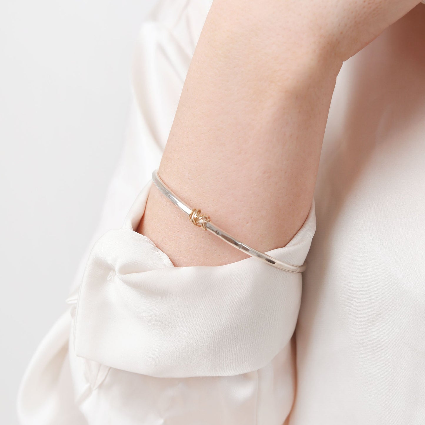 Close-up of a person wearing a delicate bracelet on a plain background
