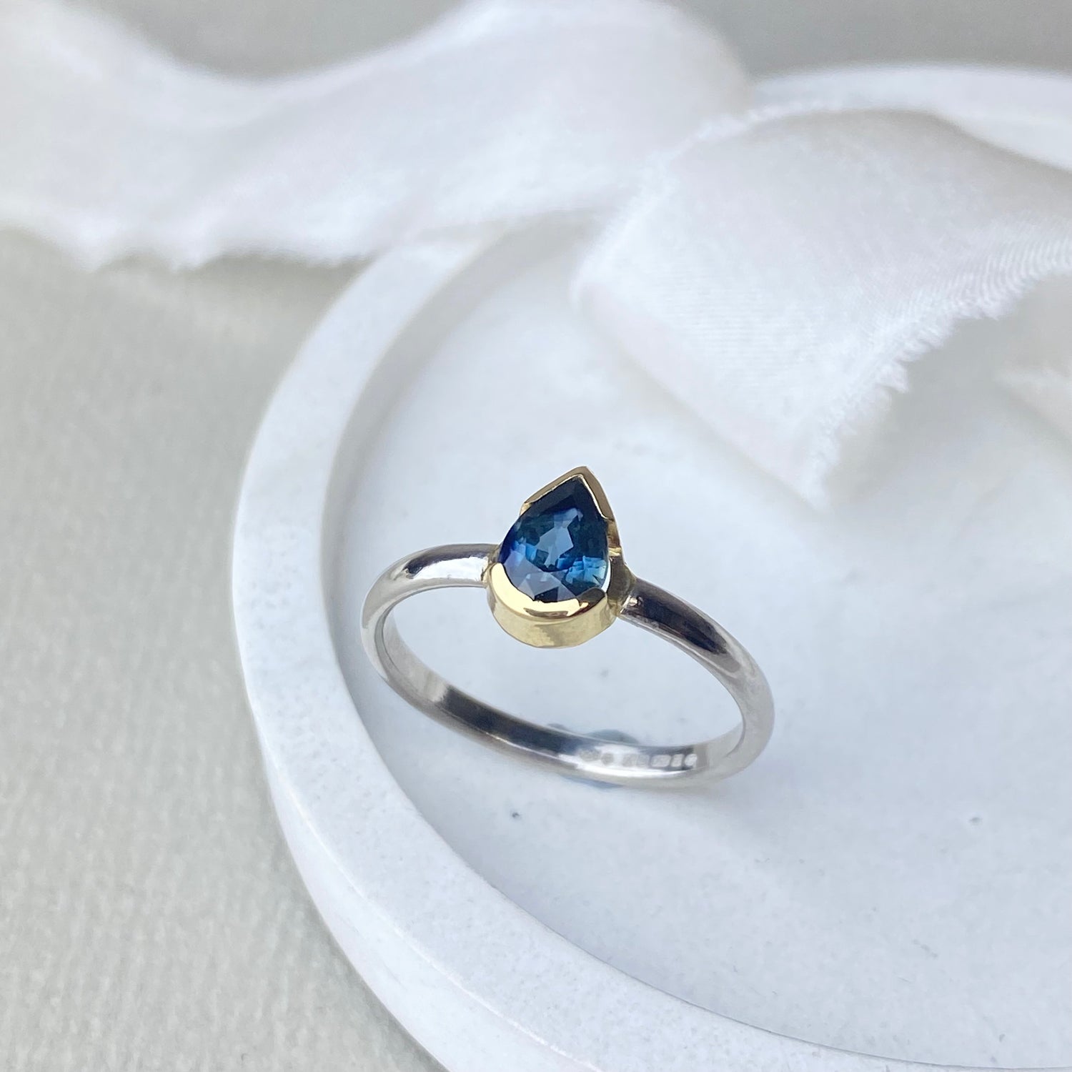 Platinum and 18ct gold Ring with a blue gemstone and gold accent on a white surface